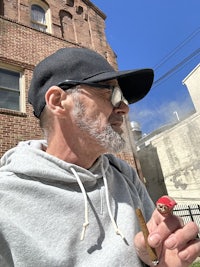 a man smoking a cigarette in front of a brick building