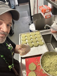 a man in a hat is preparing a batch of cookies